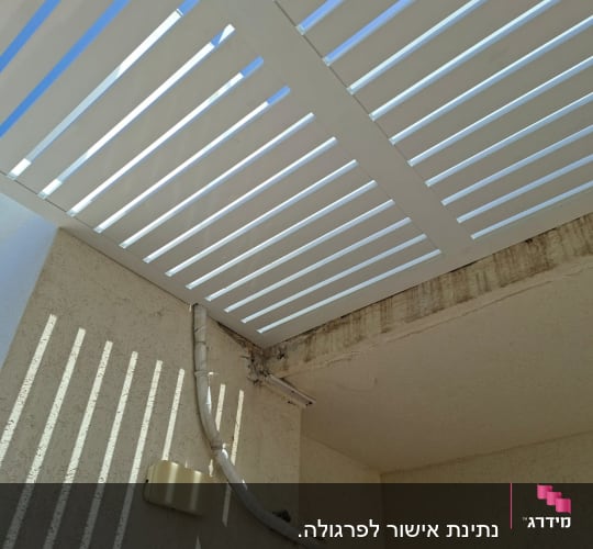 פרגולה לבנה עם צינור על קיר חיצוני